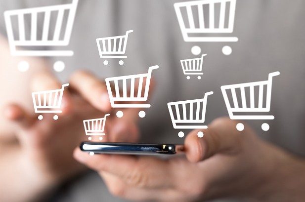 Icons weißer Einkaufswägen, die als Zeichen für E-Commerce über eine Smartphone schweben