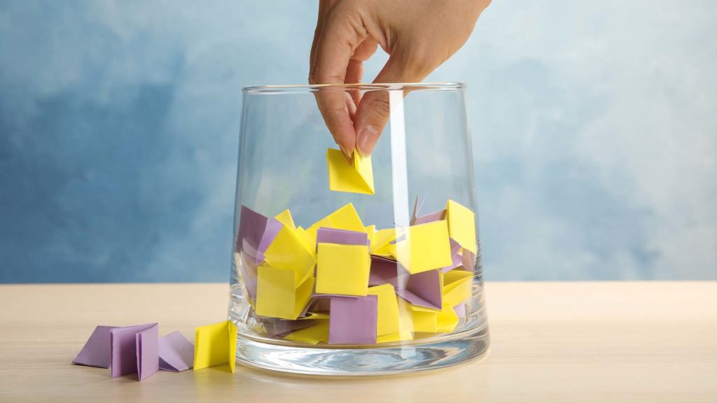 hand greift in glas und zieht einen loszettel, um an einem Gewinnspiel teilzunehmen
