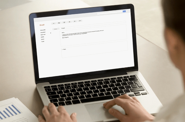 Person sitz vor einem Laptop und formuliert eine E-Mail inklusive Betreffzeile