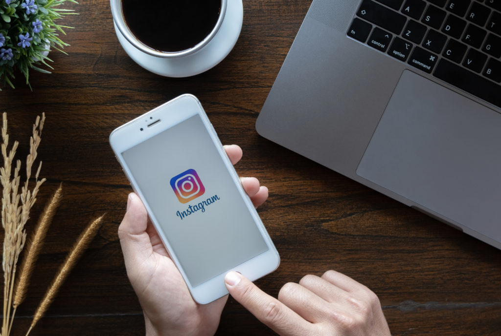 Person, die Instagram an ihrem Handy öffnet, um eine Instagram Story zu erstellen