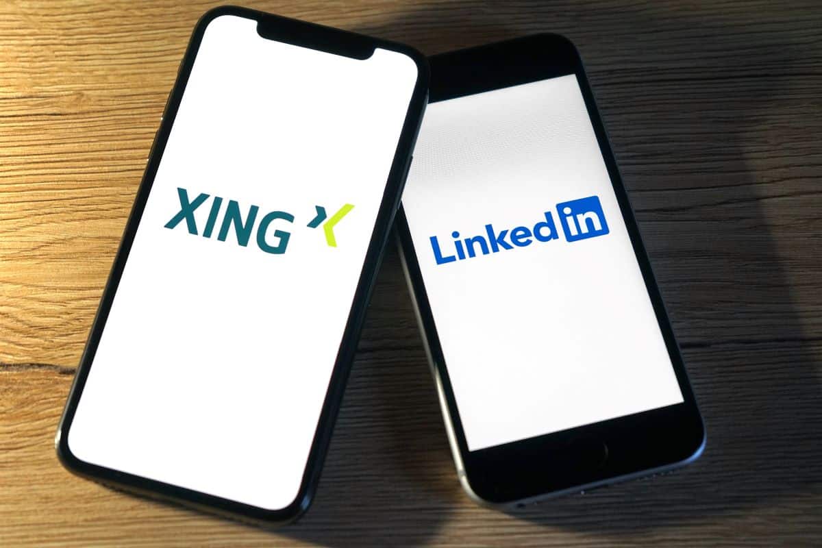 Smartphones mit den Aufschriften LinkedIn und Xing auf einem Holztisch