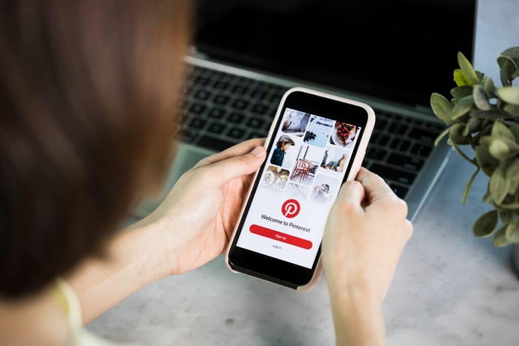 Frau öffnet Pinterest App an ihrem Smartphone und richtet eine Pinterest Ads Konto ein