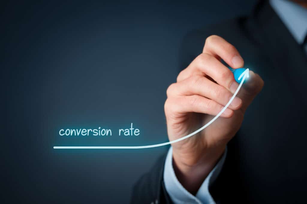 Konzept der Konversionsrate (Internetmarketing). Ein Geschäftsmann (Vermarkter) zeichnet einen wachsenden Graphen des Anstiegs der Konversionsrate.